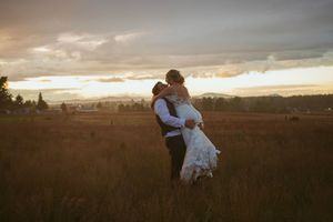 Two people in a flower field embrace as the golden sunset light illuminates the tranquil countryside landscape.
