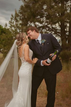 Intimate candid moment shared between newlyweds during outdoor wedding photoshoot in a field.