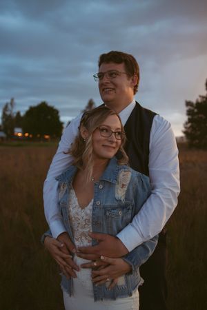 A romantic couple's portrait at sunset showing an intimate embrace in a field.