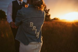 A couple stands silhouetted against a beautiful orange sunset during an outdoor photo session.