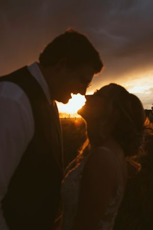 Silhouettes embrace against a dramatic sunset sky.