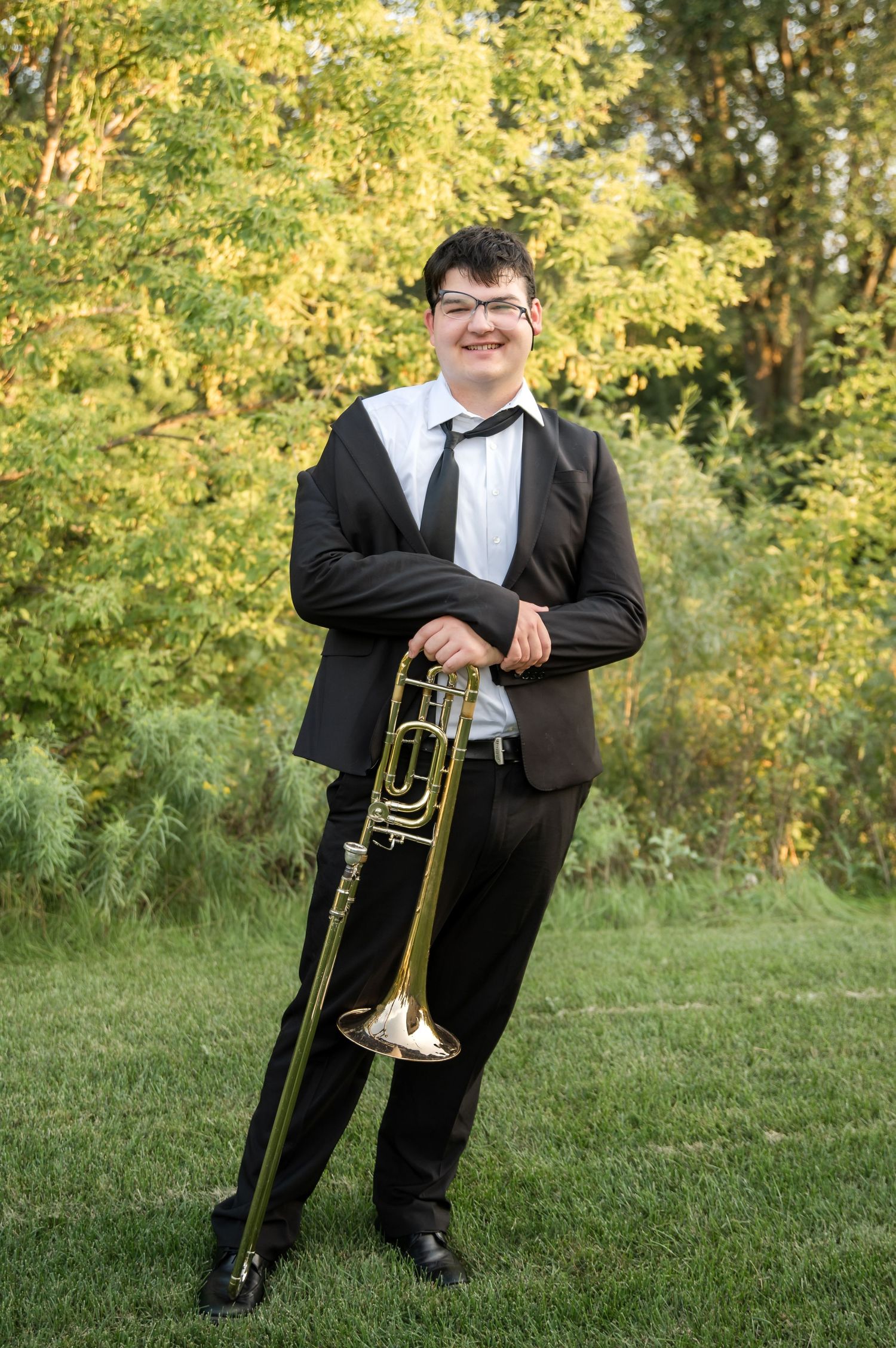 Four photos show musician in formal black tuxedo holding trumpet in outdoor setting with autumn trees.