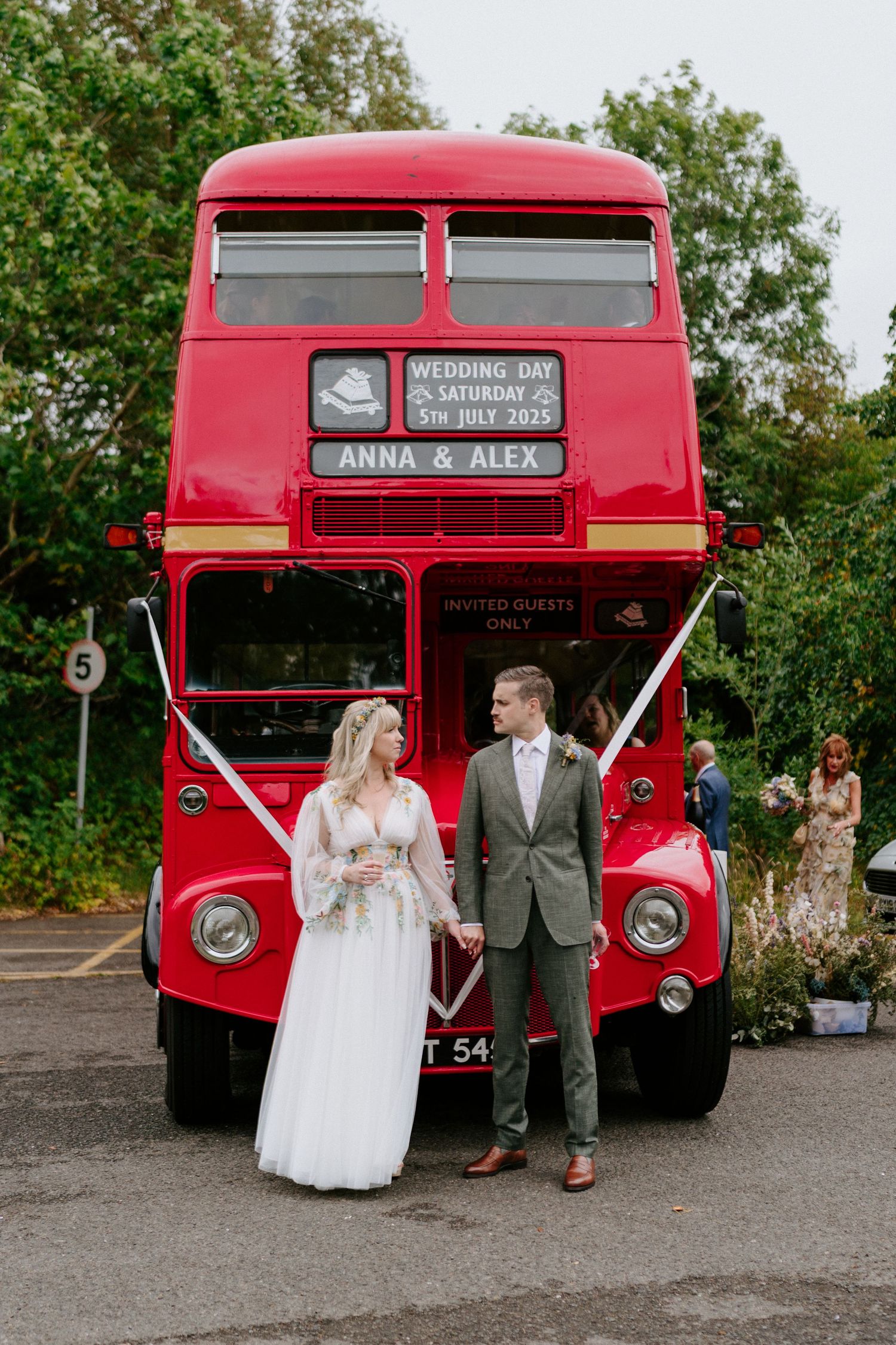 A vintage red double decker bus customized for 'Anna & Alex' serves as a unique wedding transportation vehicle.
