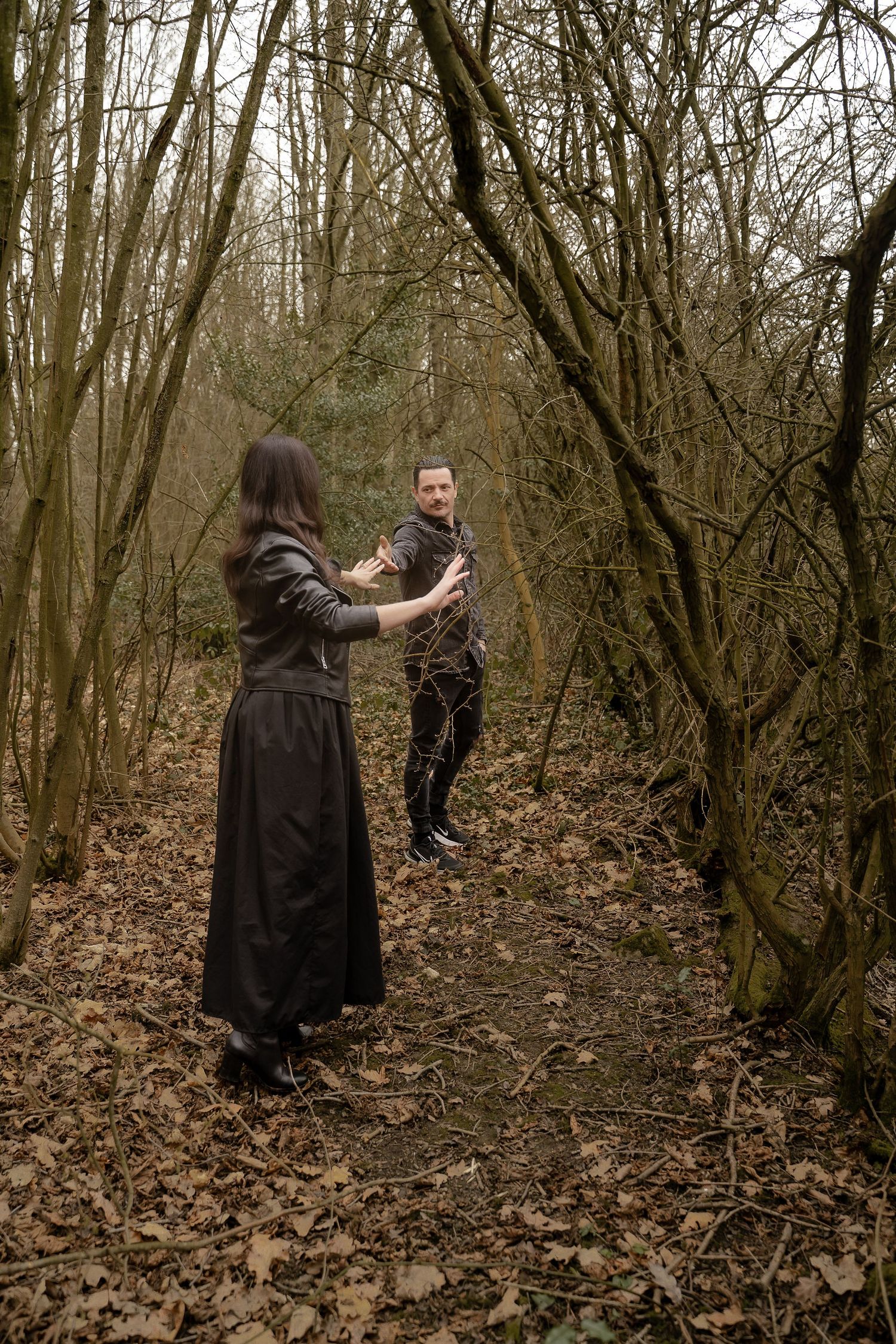 A playful moment between a couple walking through the woods near Measham, captured mid-conversation beneath a canopy of trees during a relax