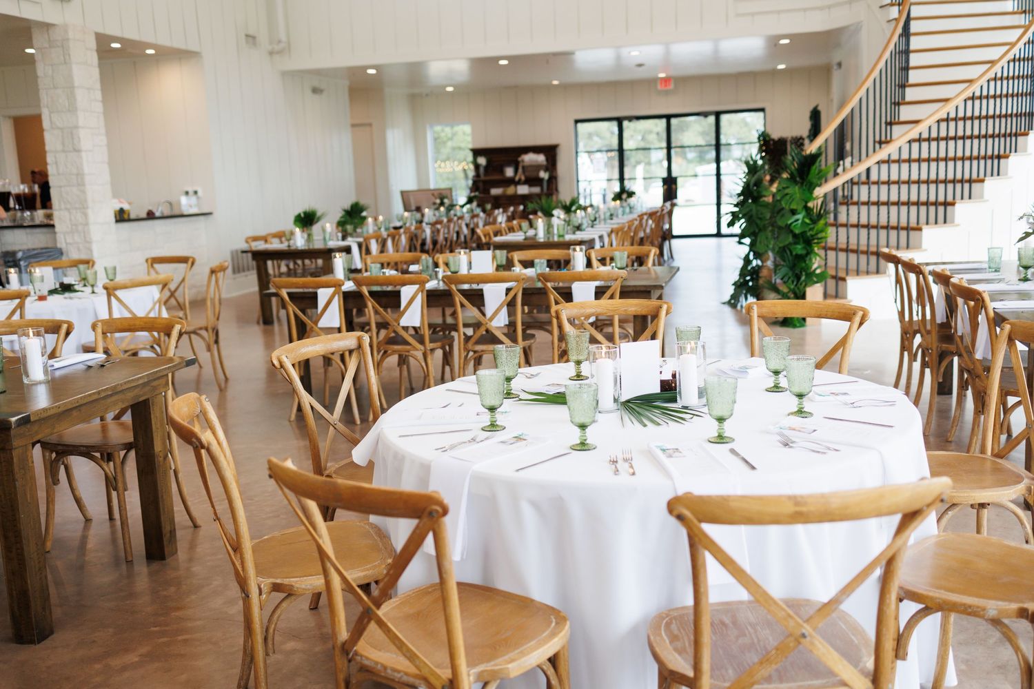 Bella Cavalli, a bright, modern venue space with round dining tables and wooden chairs arranged for an elegant tropical themed wedding.