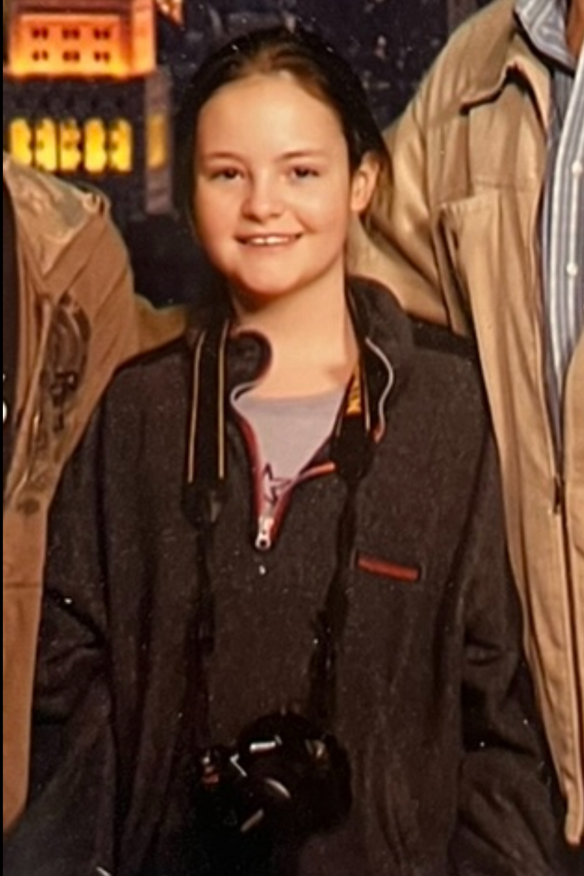Person wearing a dark hoodie poses against an illuminated background.