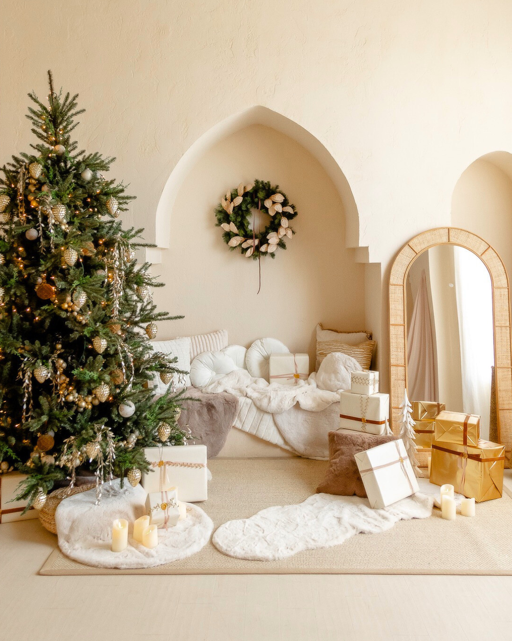 Cozy white bedroom with decorated Christmas tree, wrapped presents, and wreath in arched alcove for holiday decor.
