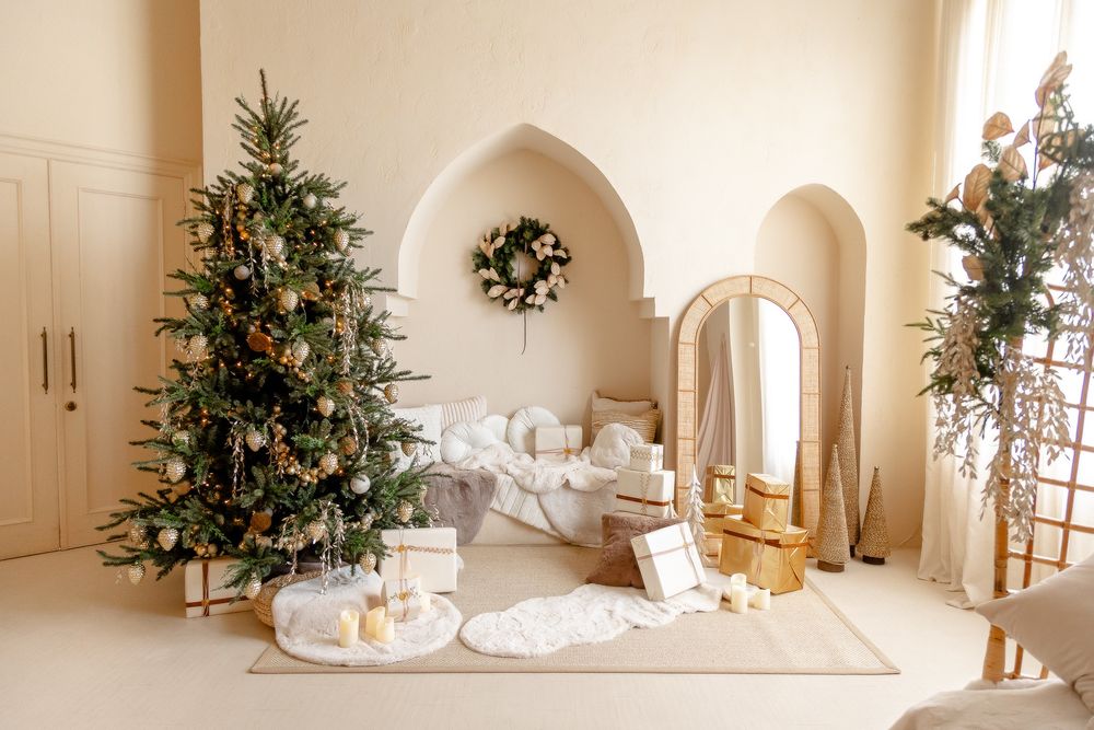 White and gold Christmas decor adorns a modern home interior with multiple illuminated trees and elegant arches.