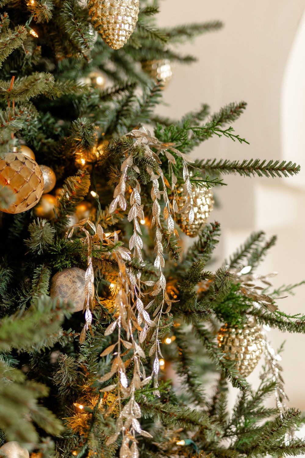 Close-up detail of Christmas tree decorations featuring sparkling icicles and gold ornaments with warm glowing lights.