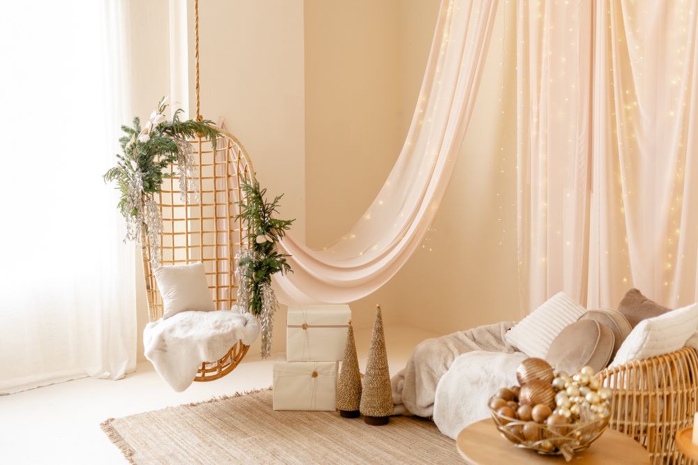 Ethereal boho-style photo studio interior with white curtains, wicker furniture, and natural light streaming through windows.