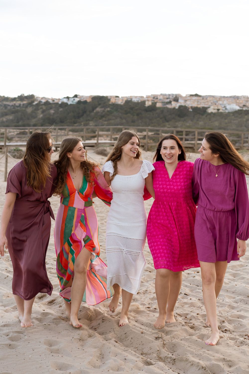 Radosna sesja panieńska na Costa Blanca. Dziewczyny w różowych sukienkach śmieją się z panną młodą.