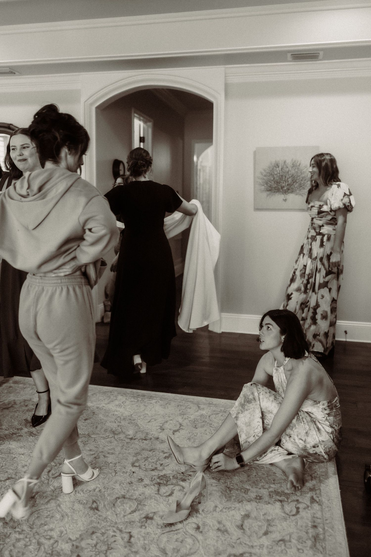 A black and white photo showing women in vintage dresses preparing for what appears to be a formal event.