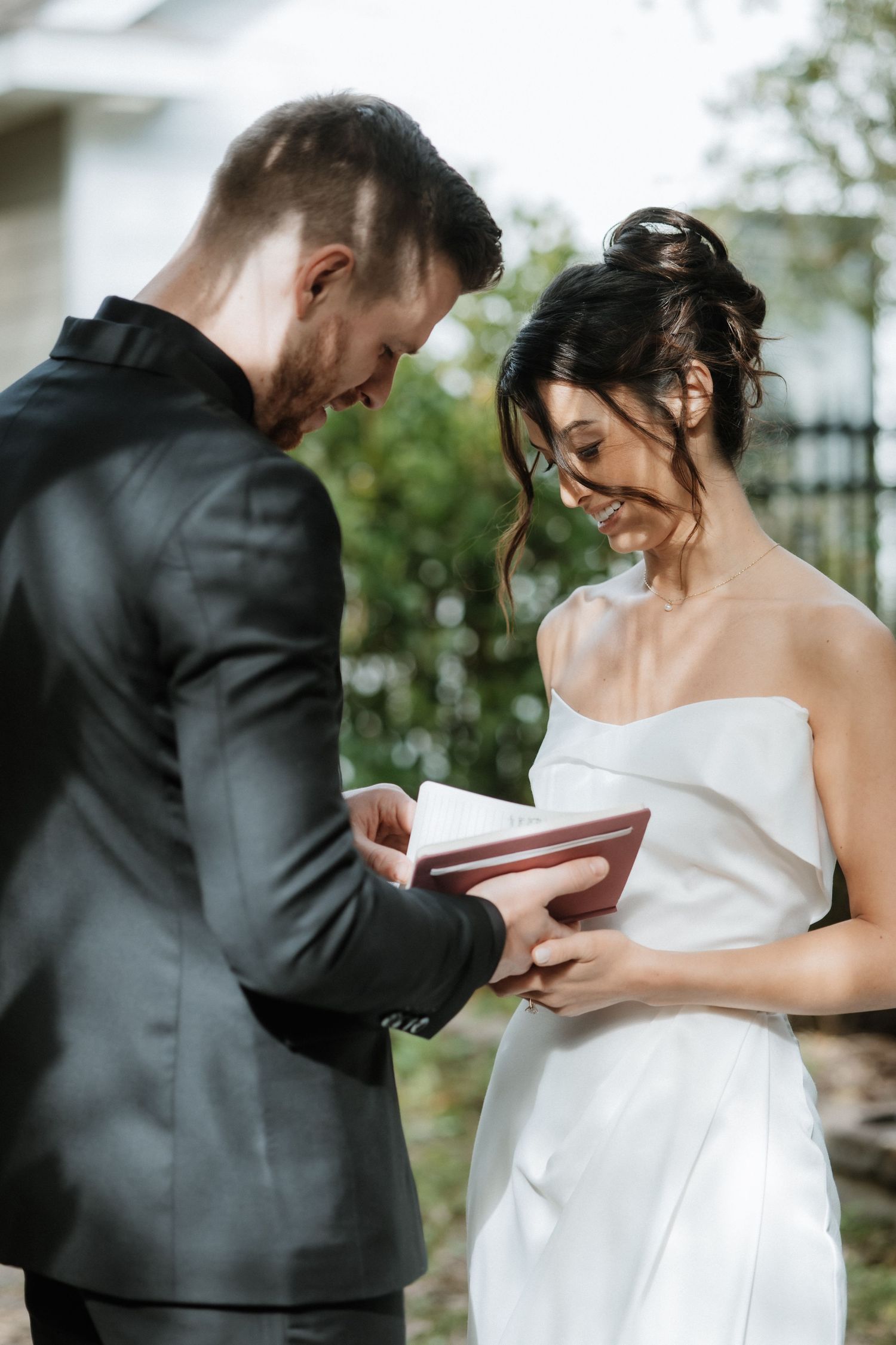 Wedding couple share an intimate moment while exchanging gifts during an outdoor ceremony.