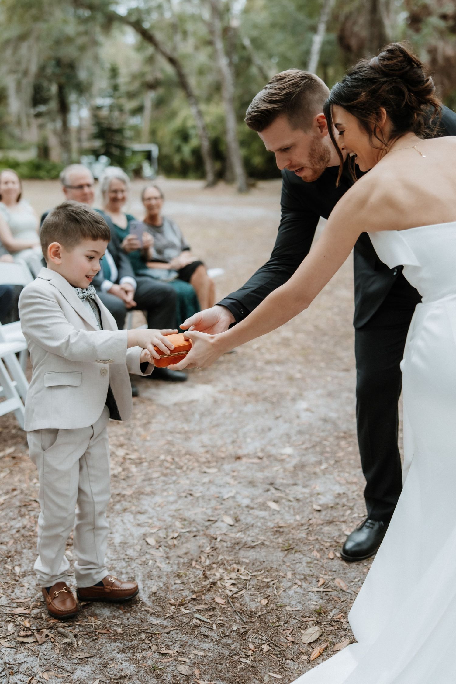 Candid moments between wedding couple and young attendee during outdoor ceremony.
