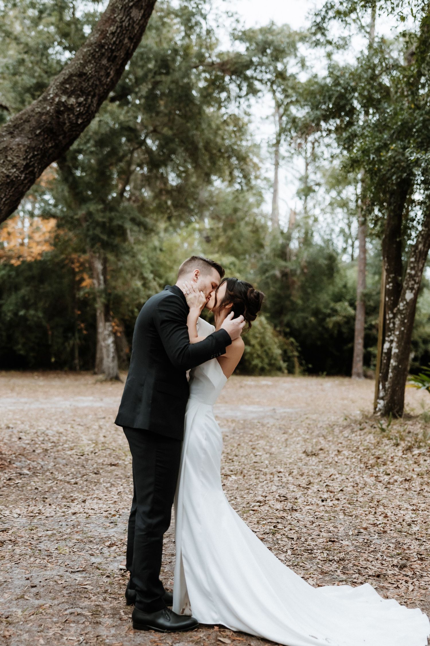 Romantic outdoor wedding moment between newlyweds surrounded by autumn trees.