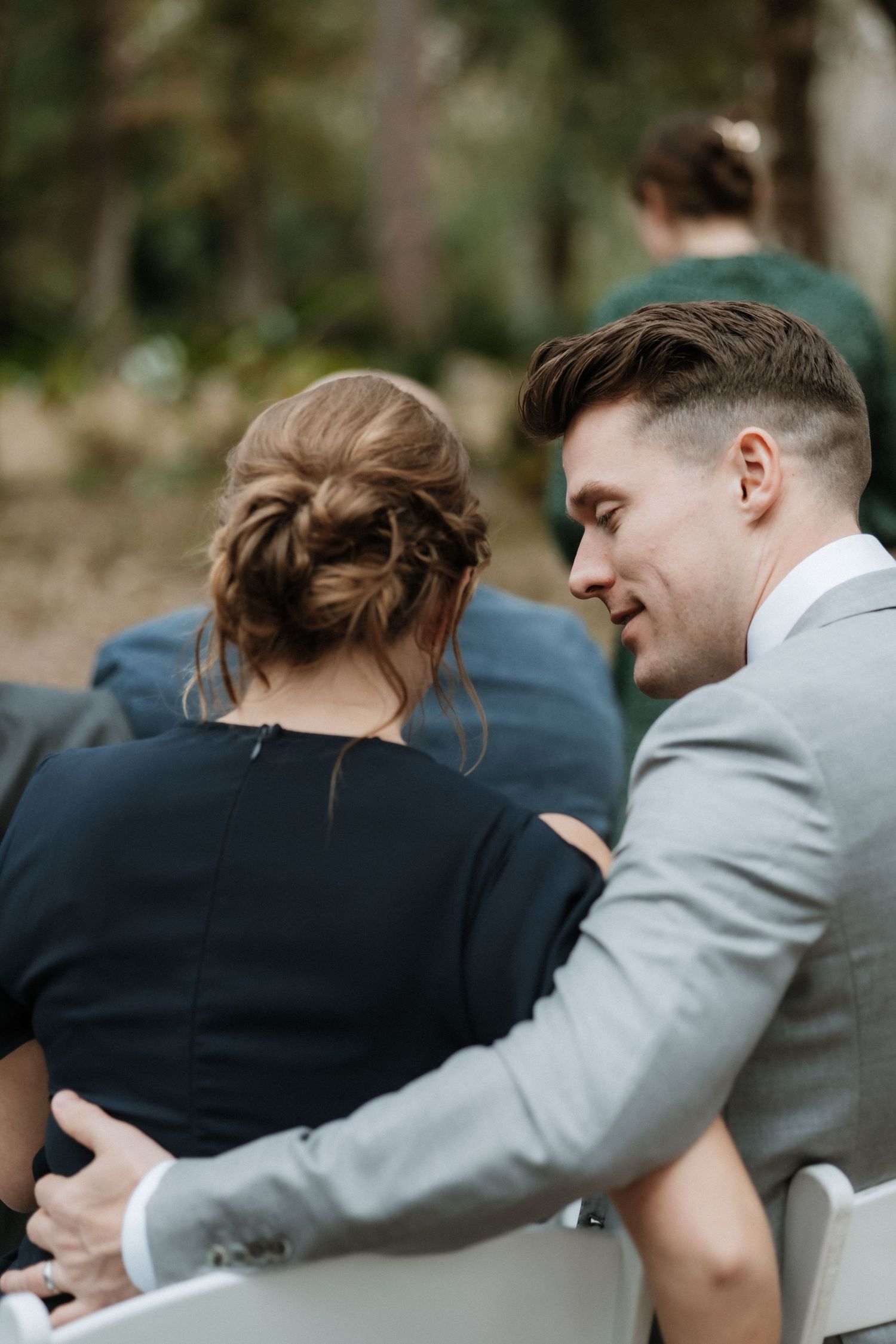 A couple shares an intimate moment during what appears to be an outdoor wedding ceremony.