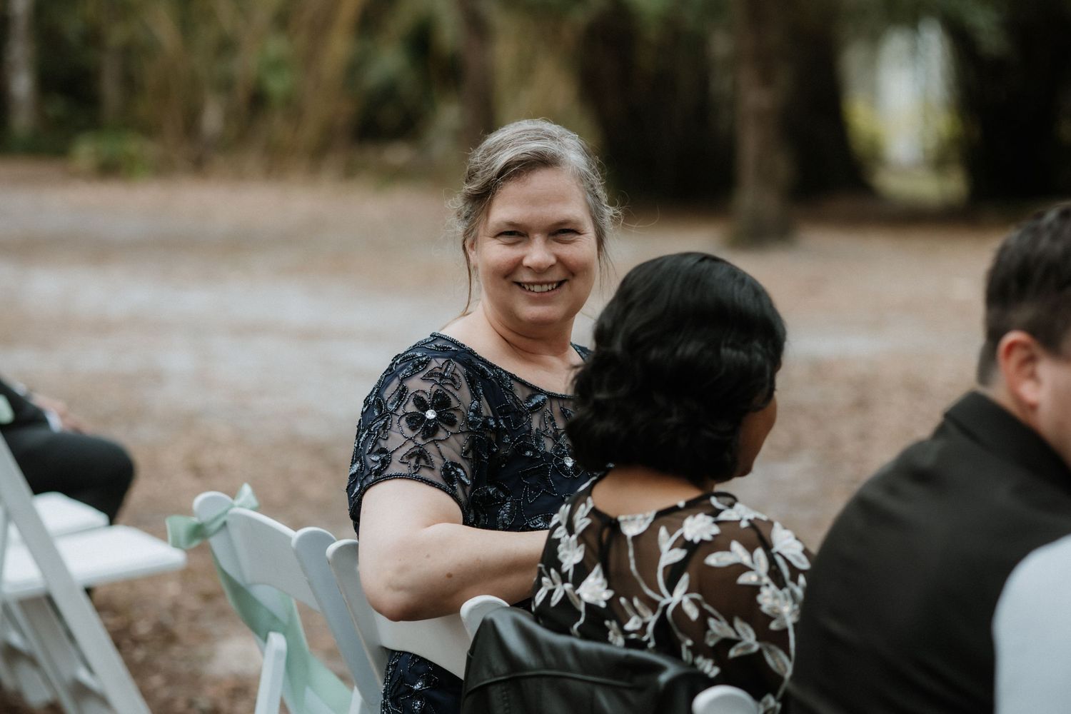 Guests enjoying conversation at an outdoor event with folding chairs visible.