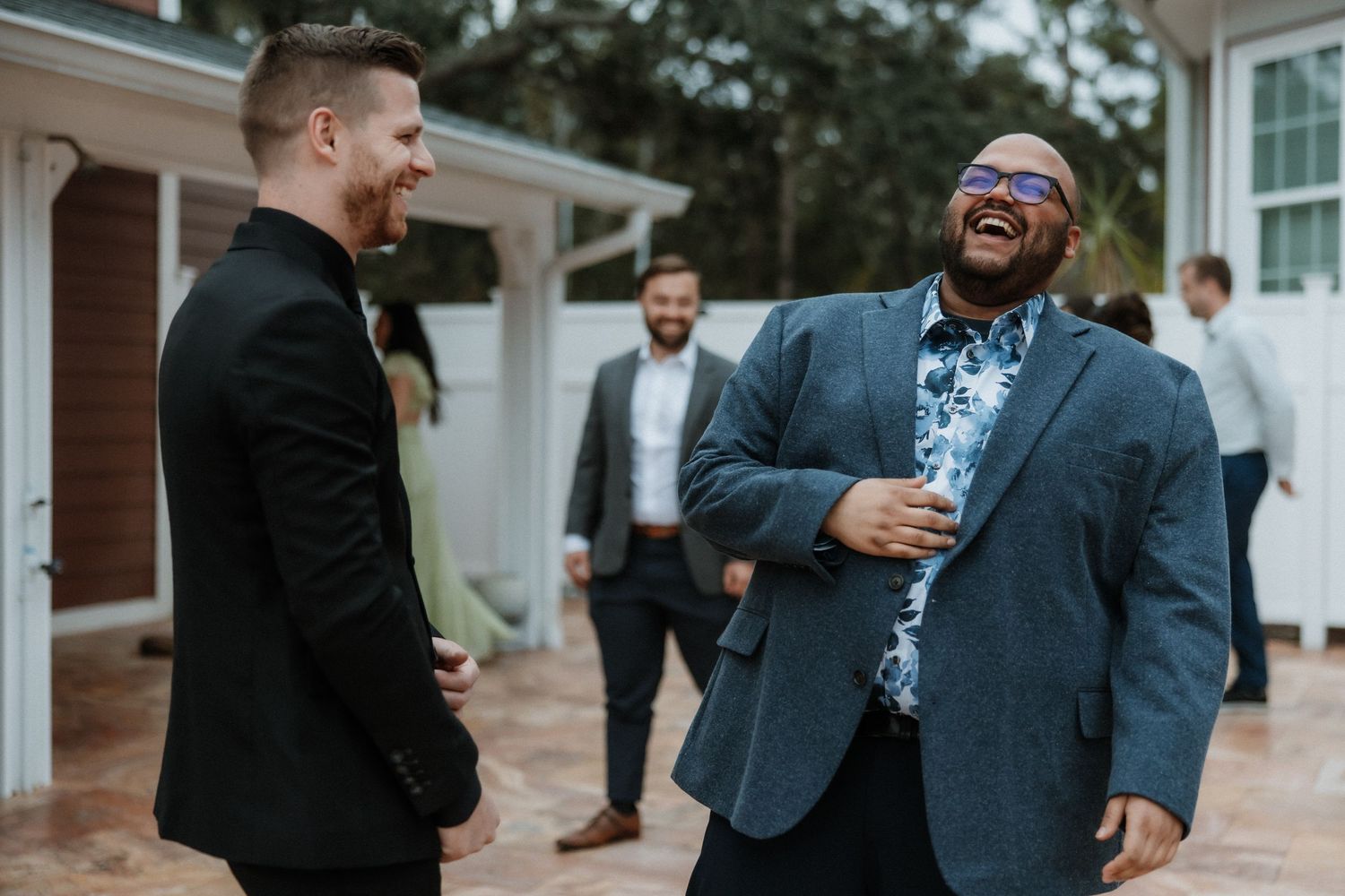 Two guests share a jovial moment and laugh together at a casual outdoor event.