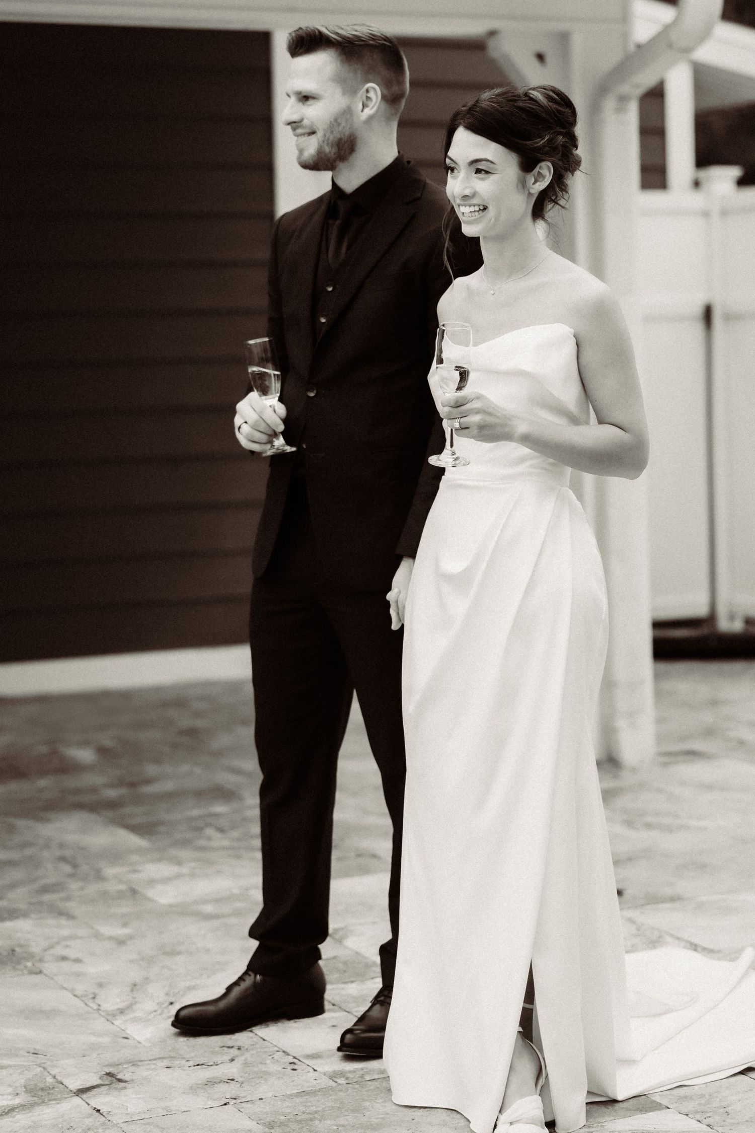 Black and white wedding photograph showing a romantic moment between newlyweds on a patio.