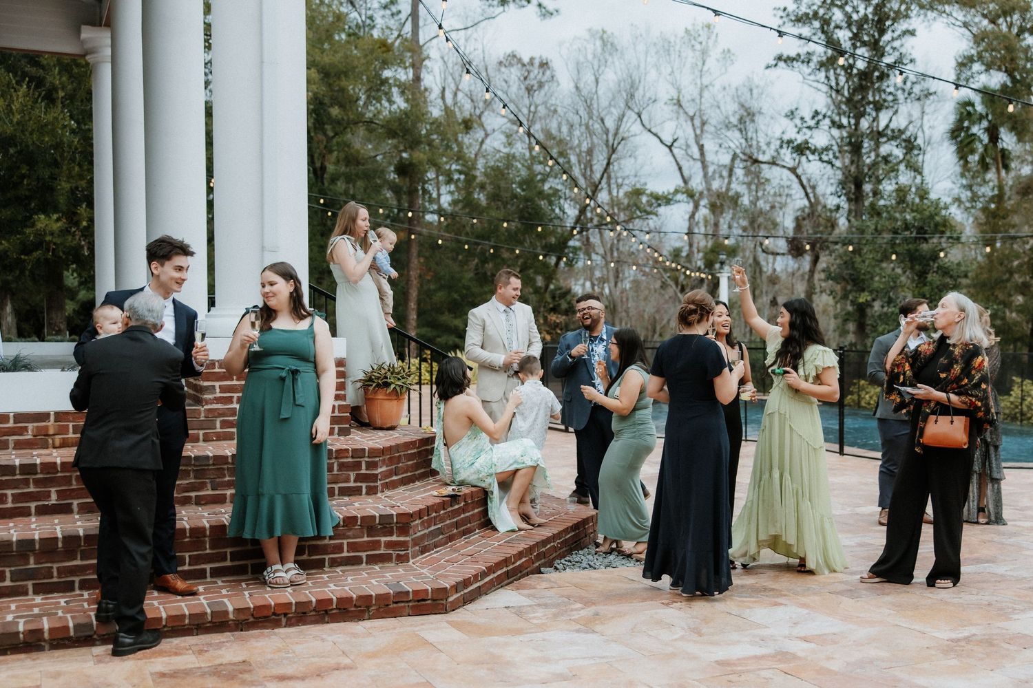 Wedding party gathered on brick steps during an outdoor reception celebration.