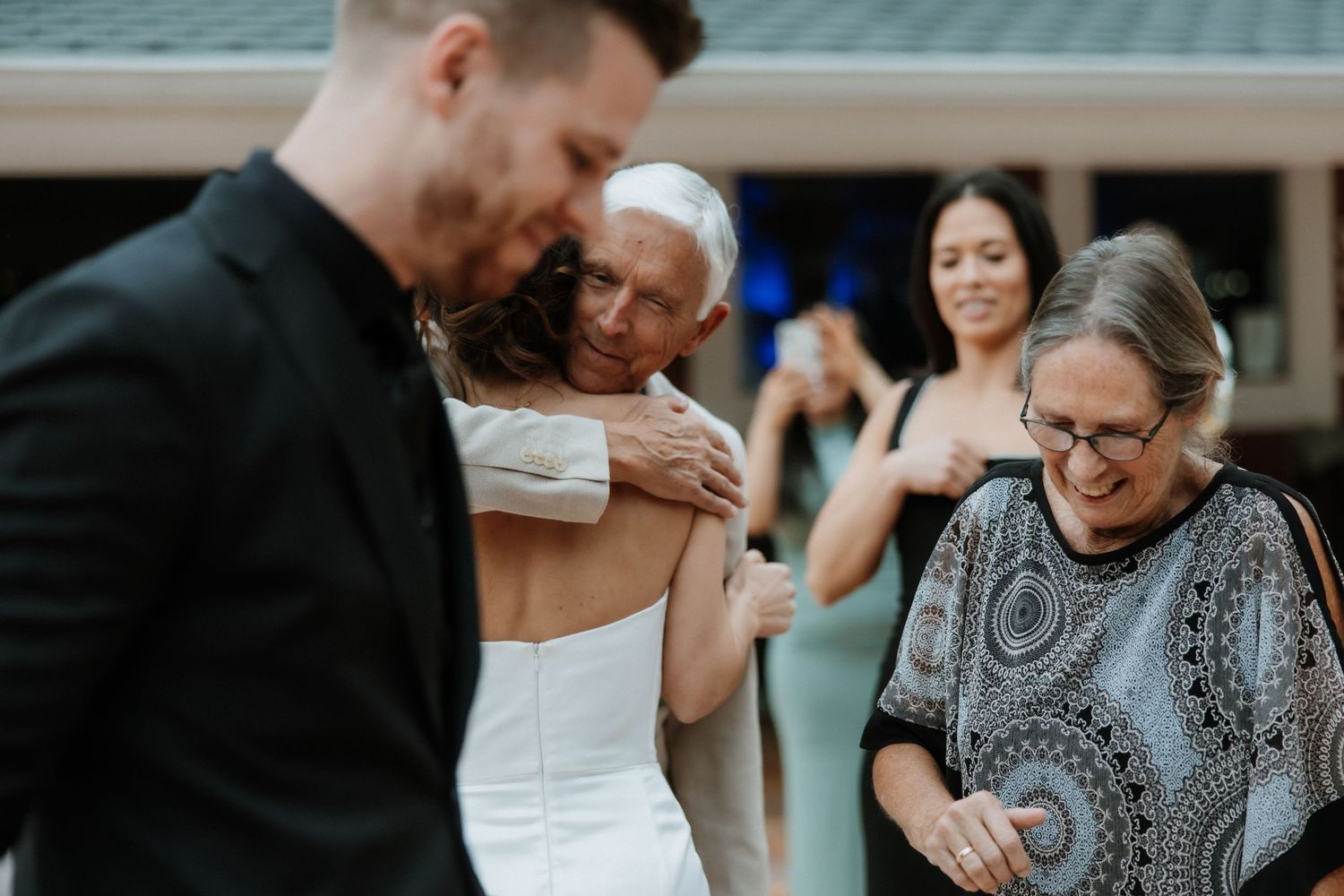 Wedding guests share emotional moments during reception celebrations outdoors.