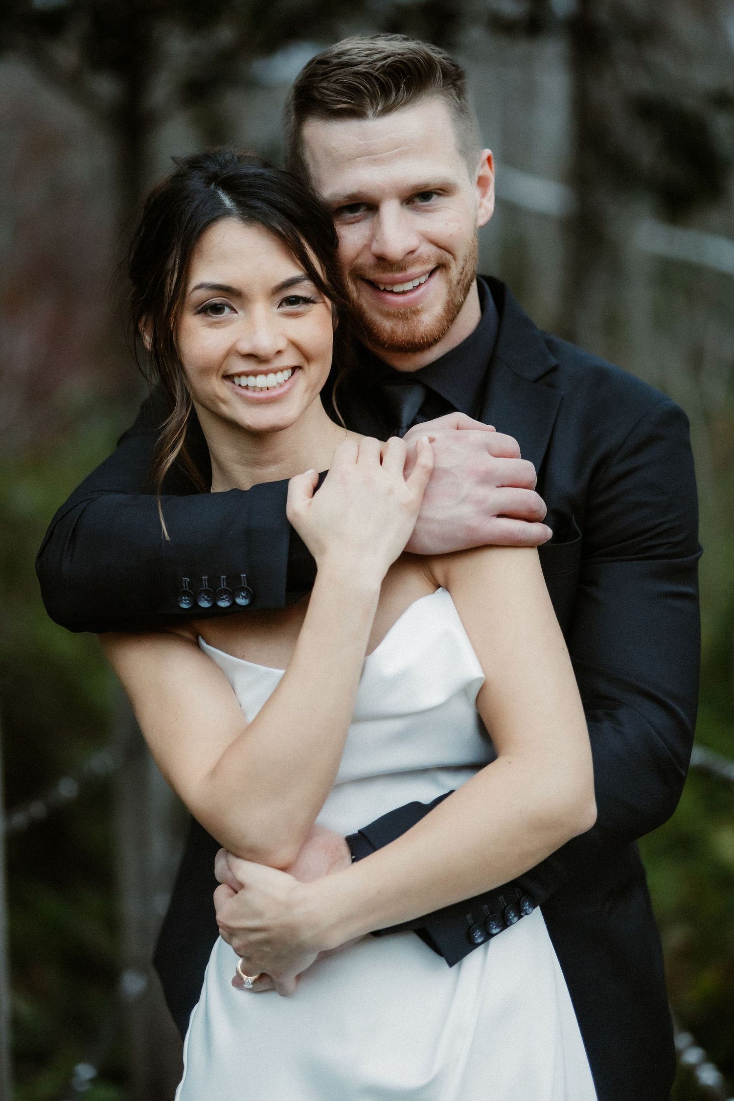 A romantic outdoor portrait featuring embracing couple in formal attire.