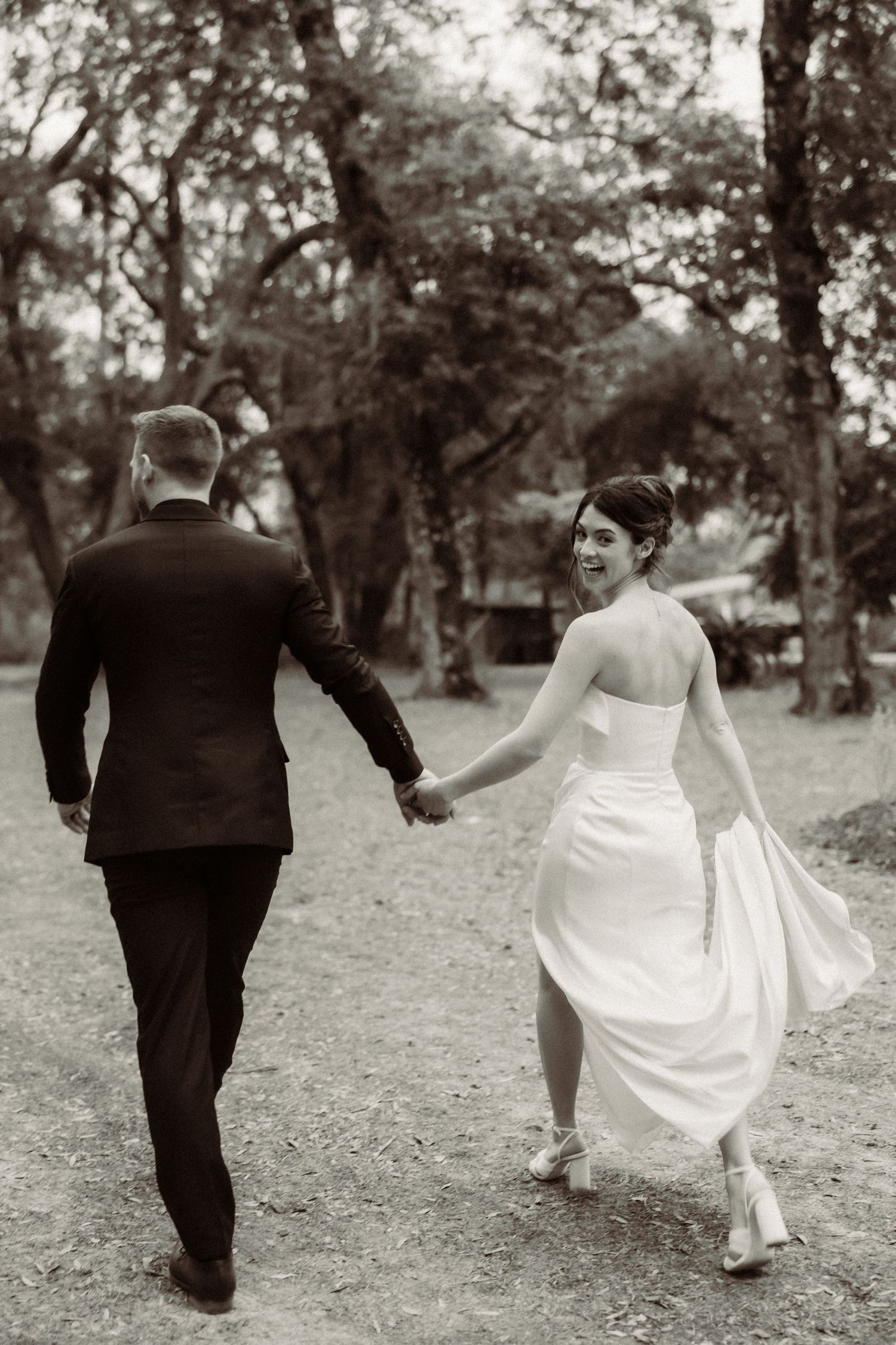 Black and white photo of couple walking through a scenic garden pathway.