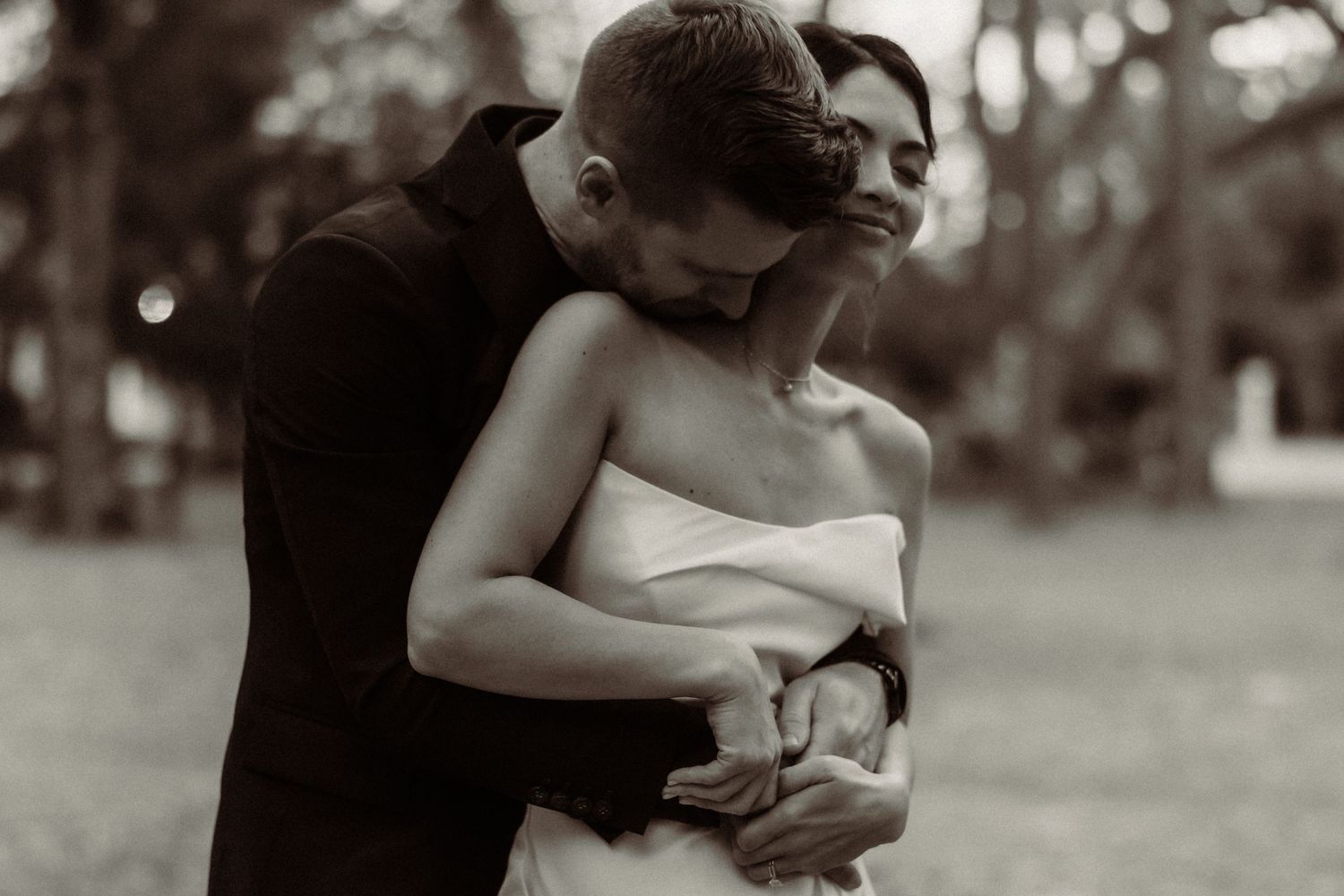 Romantic embrace captured in soft black and white tones during wedding celebration.