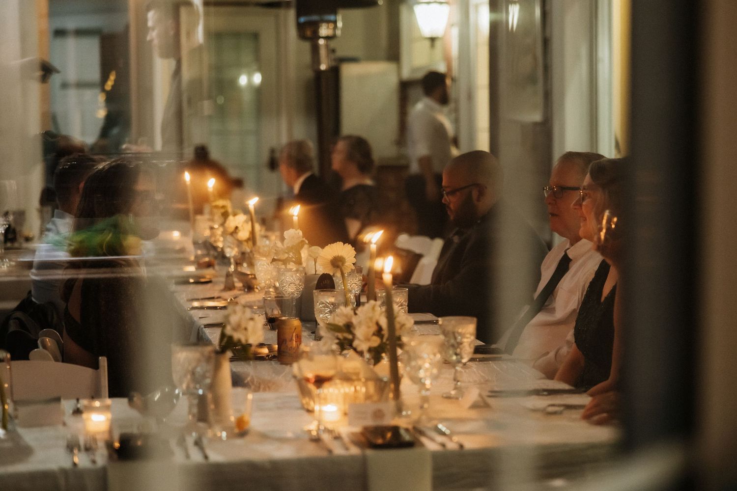 Elegant candlelit wedding reception dinner table with warm ambient lighting.