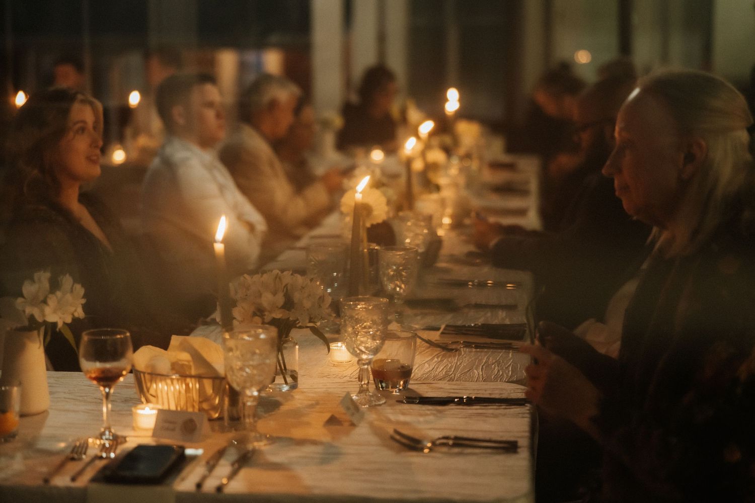 Intimate dinner reception setting with glowing candles and table settings.