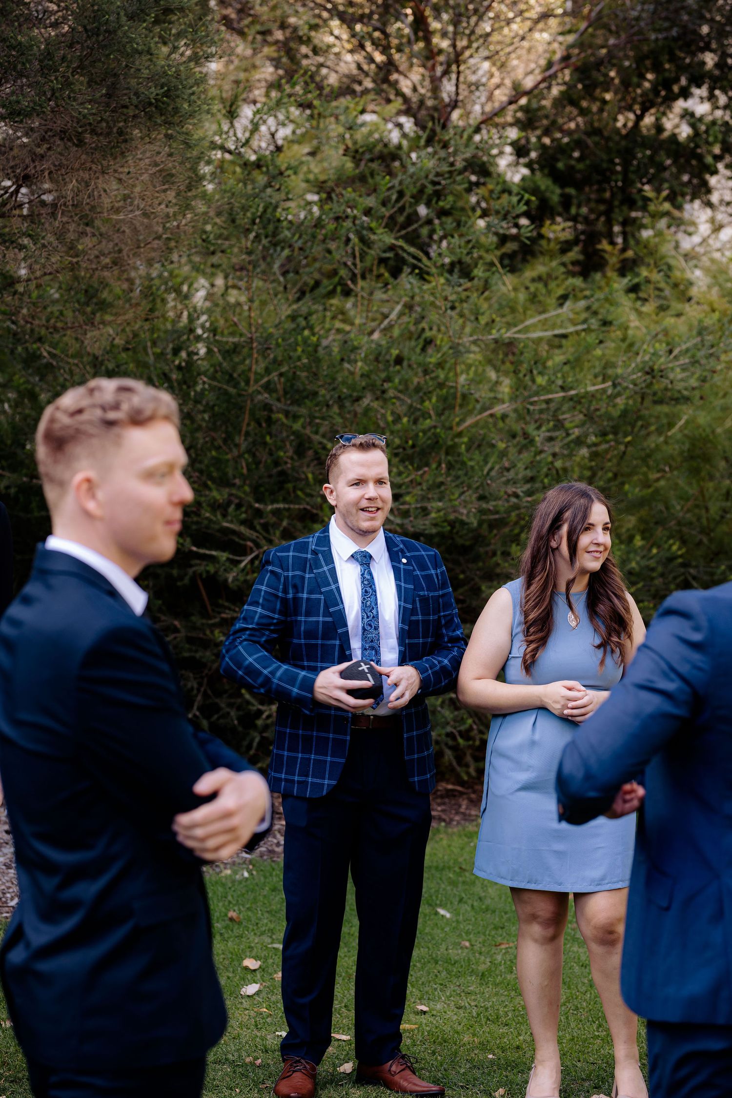 Friends laughing together outdoors in casual and formal attire during a candid photo series in a garden setting.