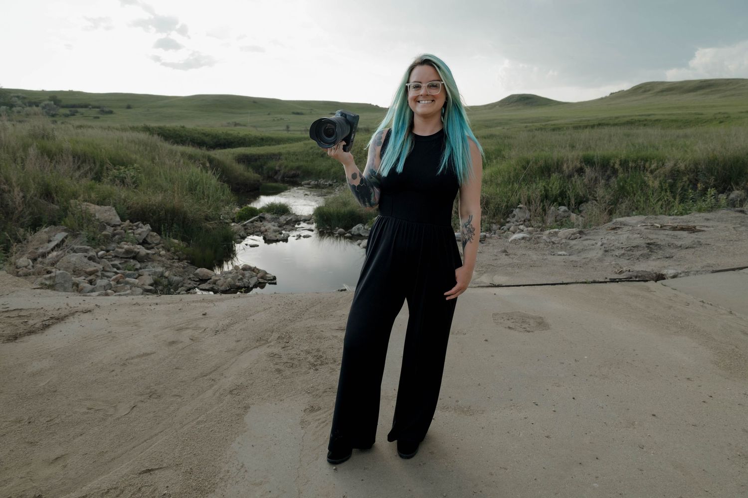 Person with long blonde hair walks along rugged coastal pathway with scenic cliffs and ocean views in the background. Bismarck, ND