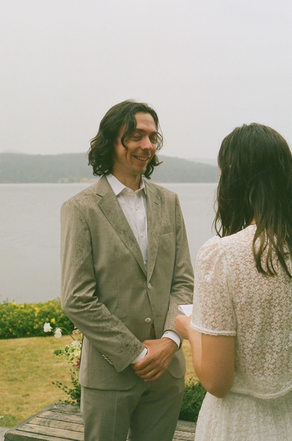 A couple shares candid moments together on a misty coastal meadow.