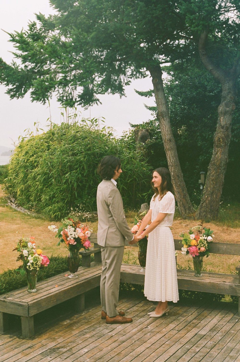 A wooden deck overlooking water with trees and natural lighting creates a romantic setting.