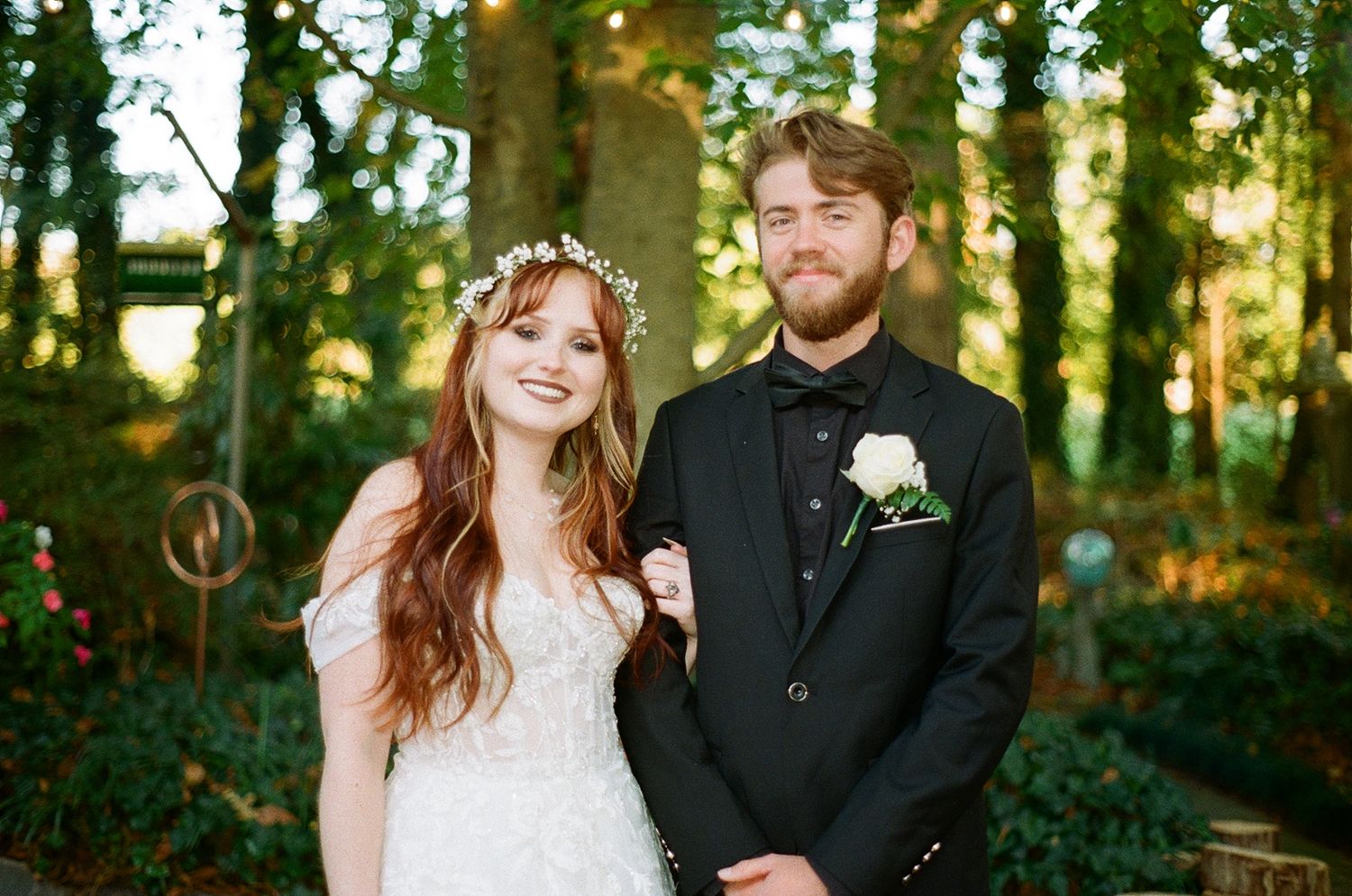 A romantic nighttime wedding scene with a floral arch decorated in white flowers and twinkling string lights on film and super 8 coverage SC