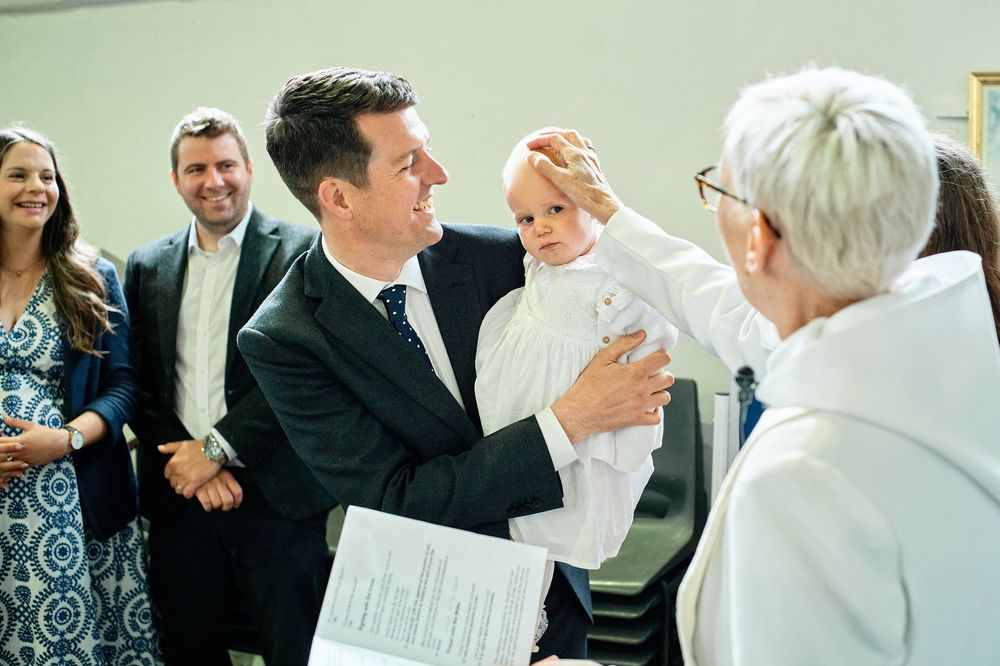 A christening ceremony takes place as guests gather to witness the special moment in a church setting.