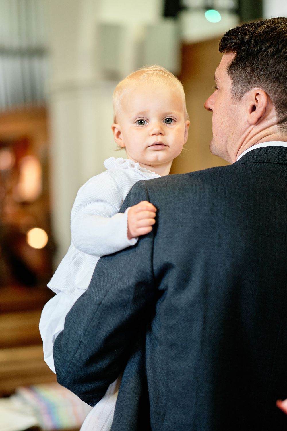 Series of heartwarming moments showing a baby in white outfit being held against someone wearing a dark suit.