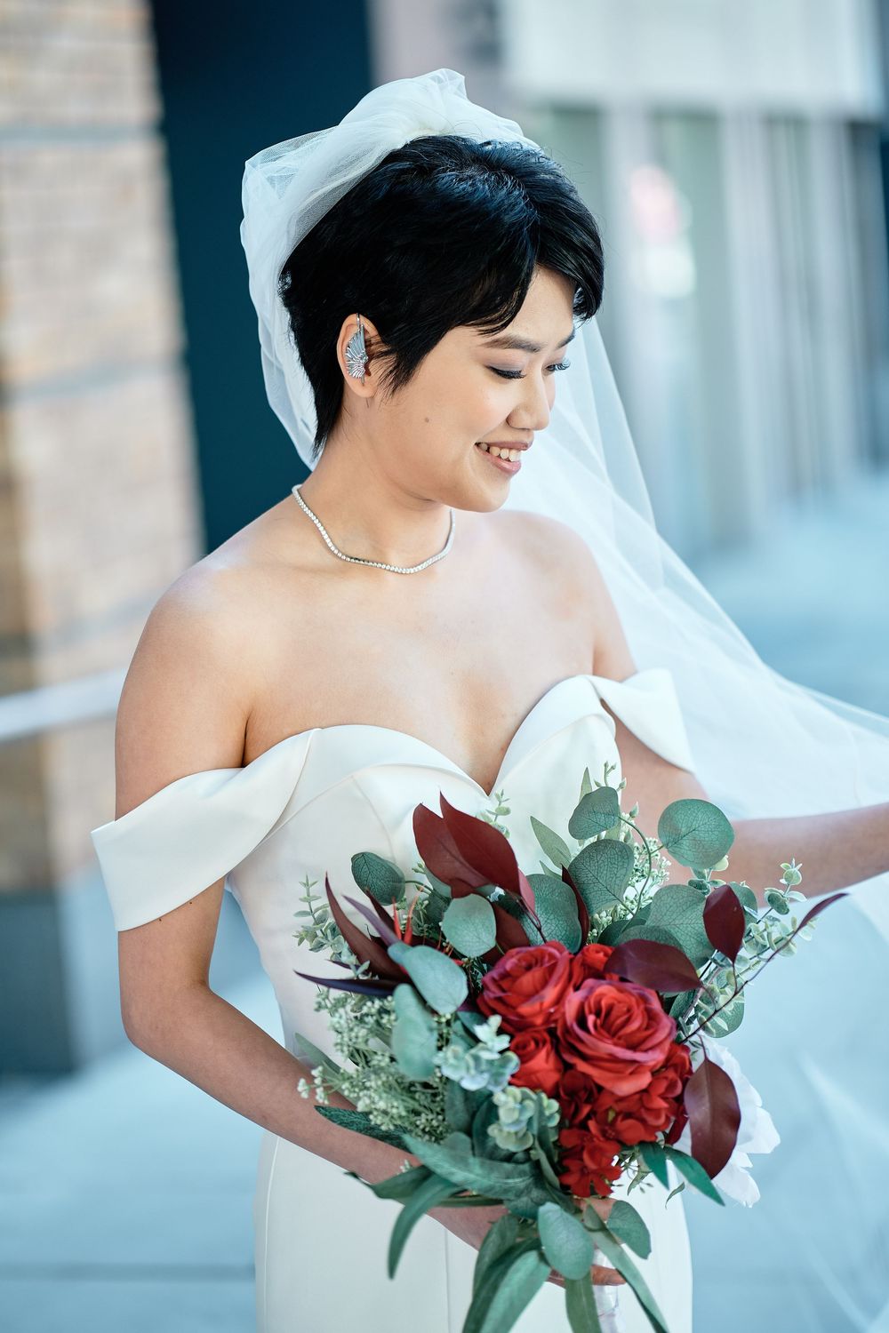 A bride in white holds a romantic red and green bouquet featuring roses and eucalyptus in a series of elegant portraits.