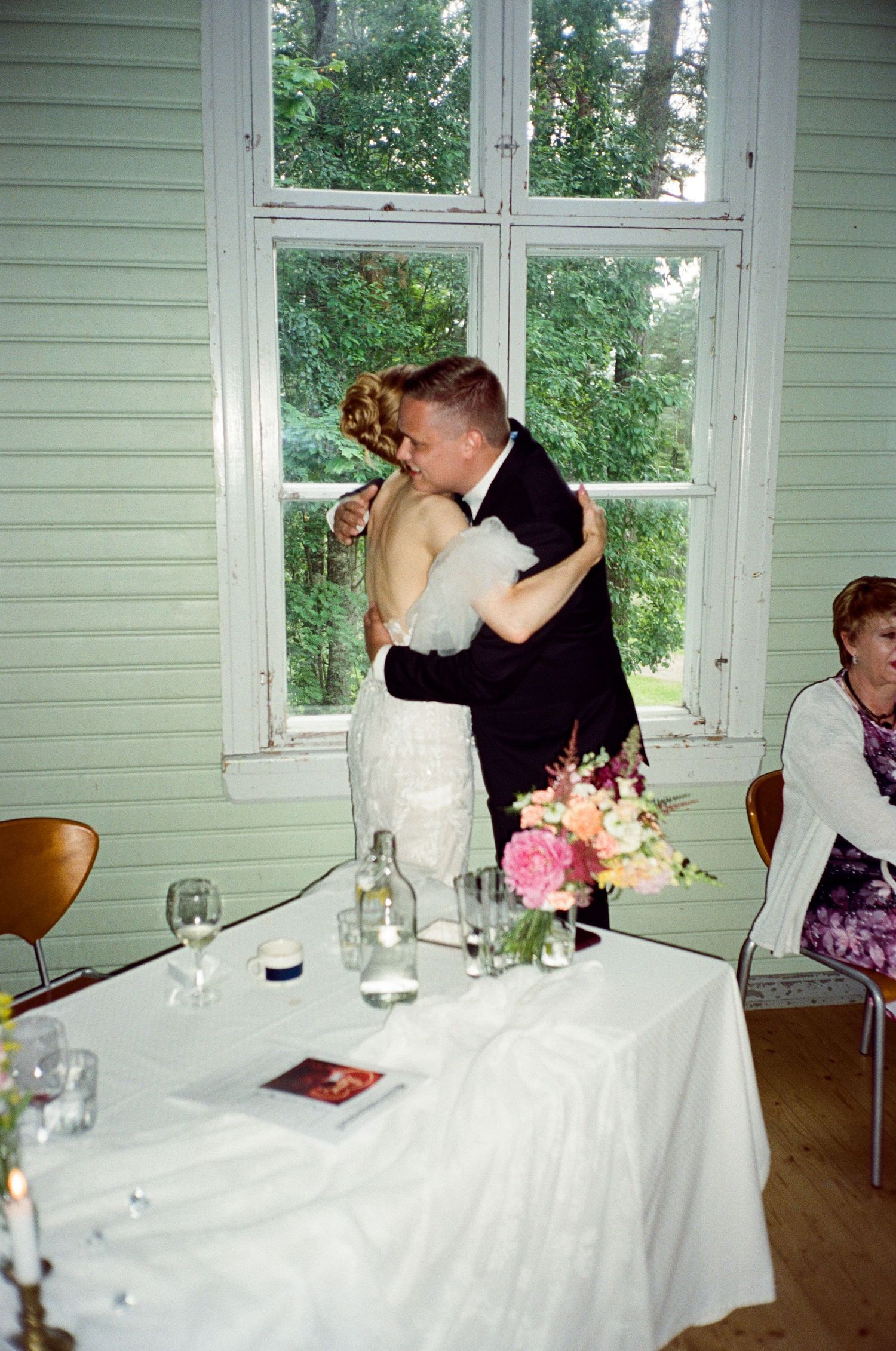 A romantic diptych of a newlywed couple sharing their first kiss at their wedding reception with floral centerpieces.