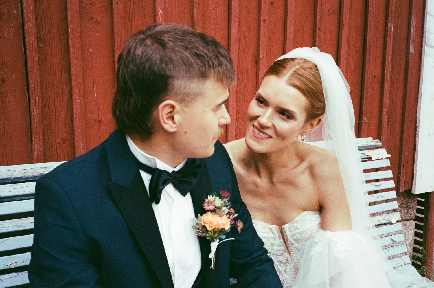 A series of romantic wedding moments showing couples sharing tender kisses in front of a red barn backdrop.