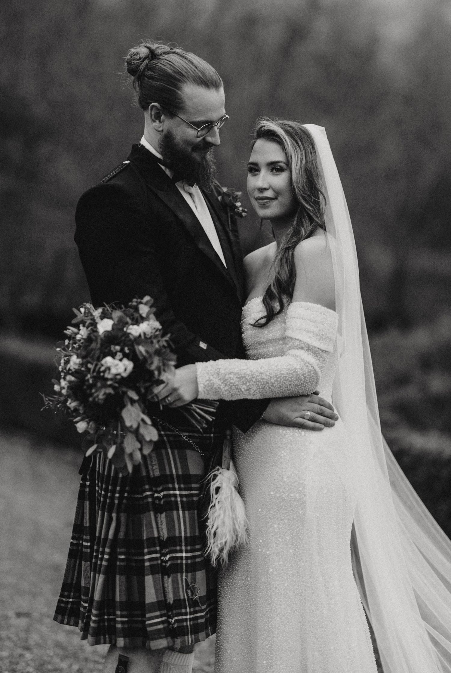A Scottish wedding couple in formal attire share romantic moments in black and white photographs outdoors.