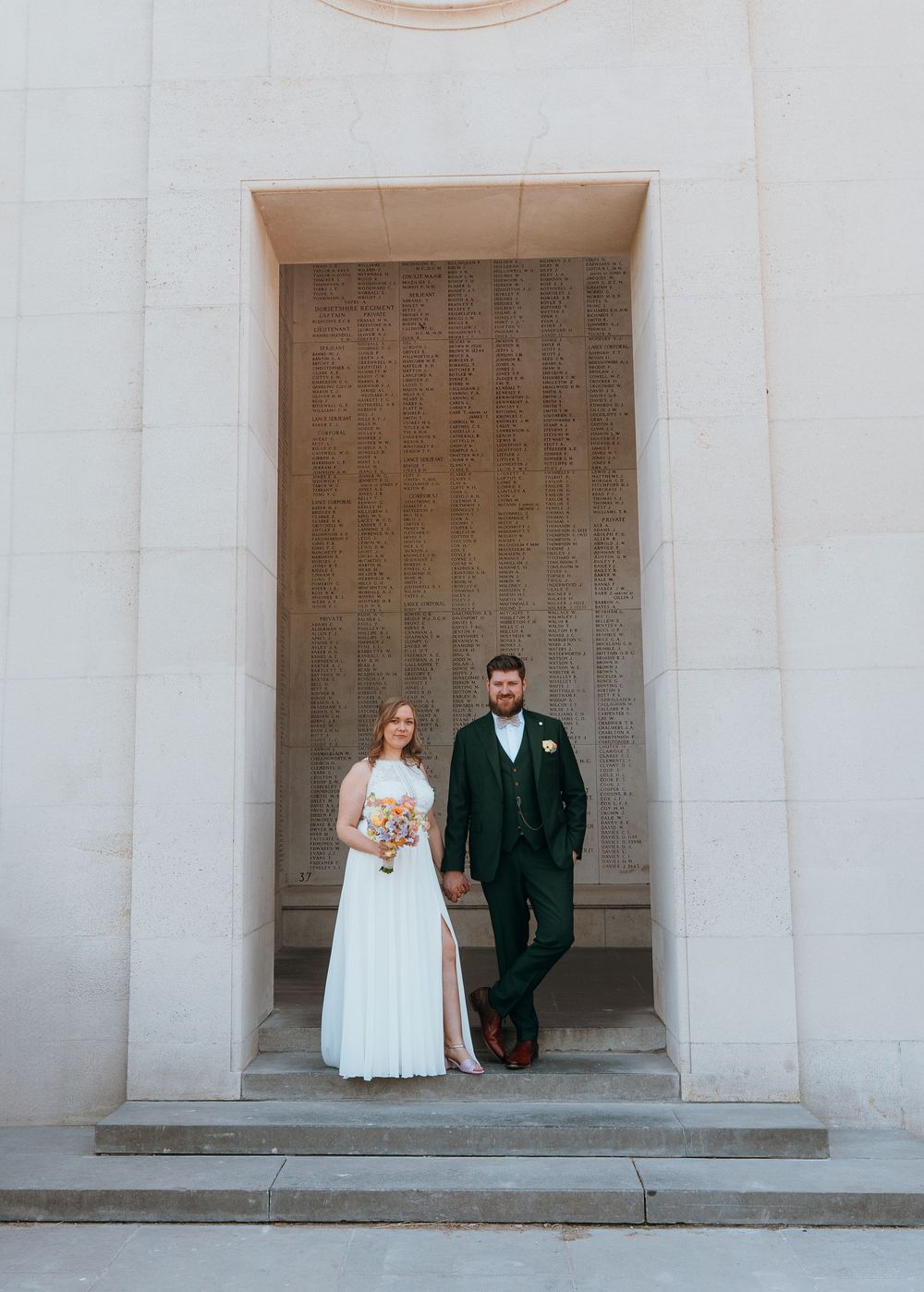 A couple stands in an elegant stone archway during their wedding ceremony.