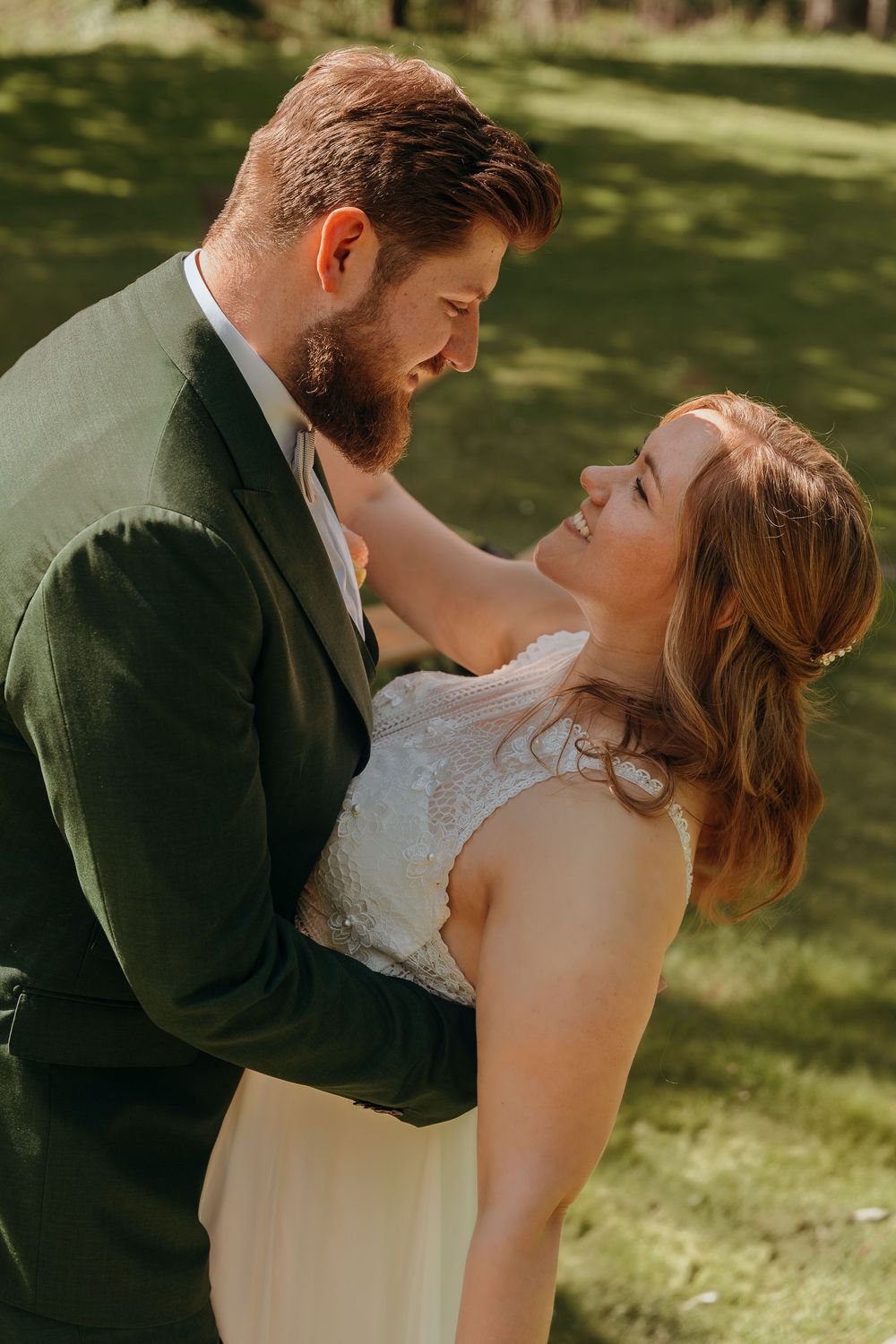 Sunlit outdoor wedding scene on a grassy lawn in warm golden light.