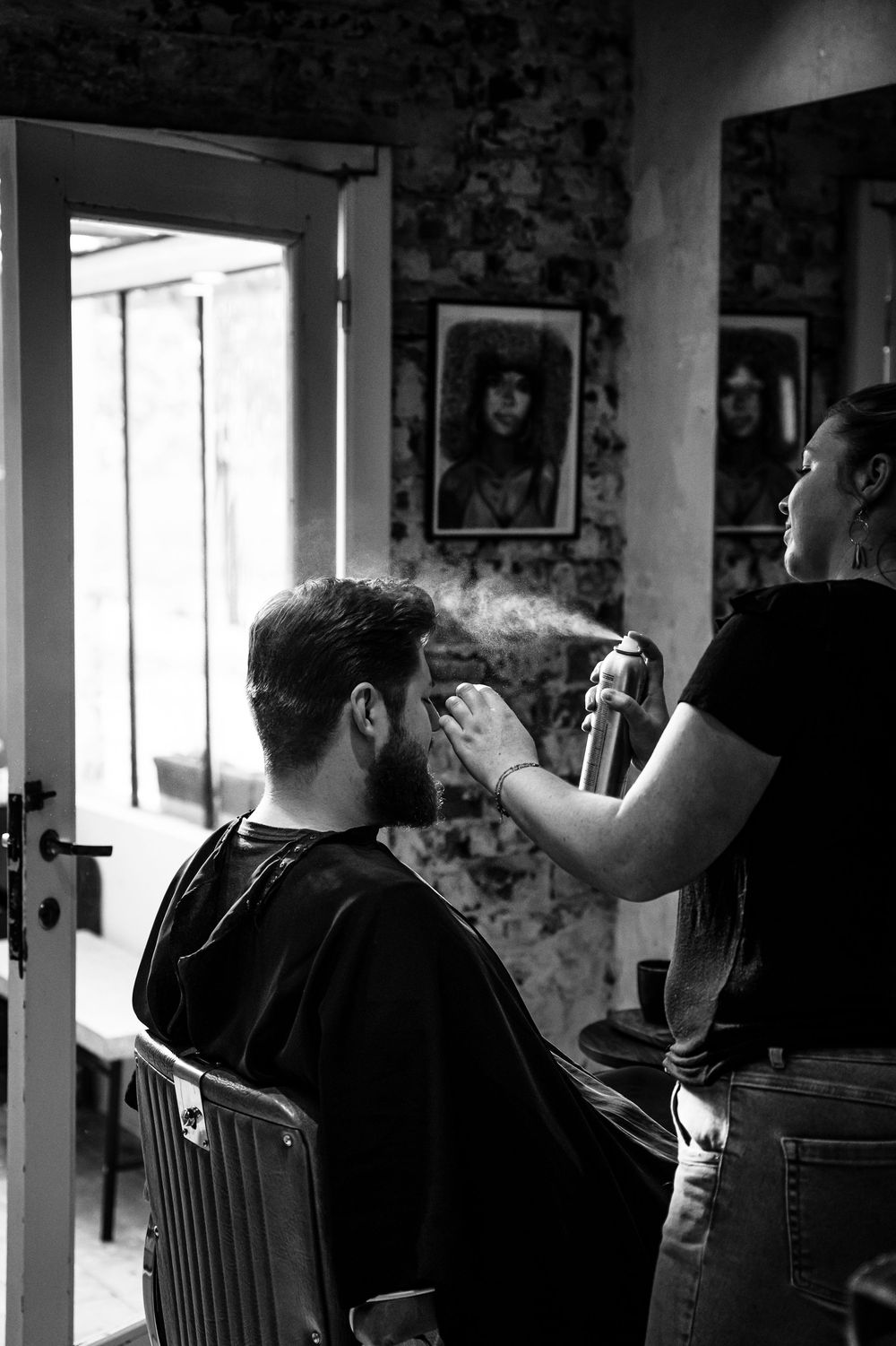 Black and white photo of a haircut preparation in a vintage-style barbershop setting.
