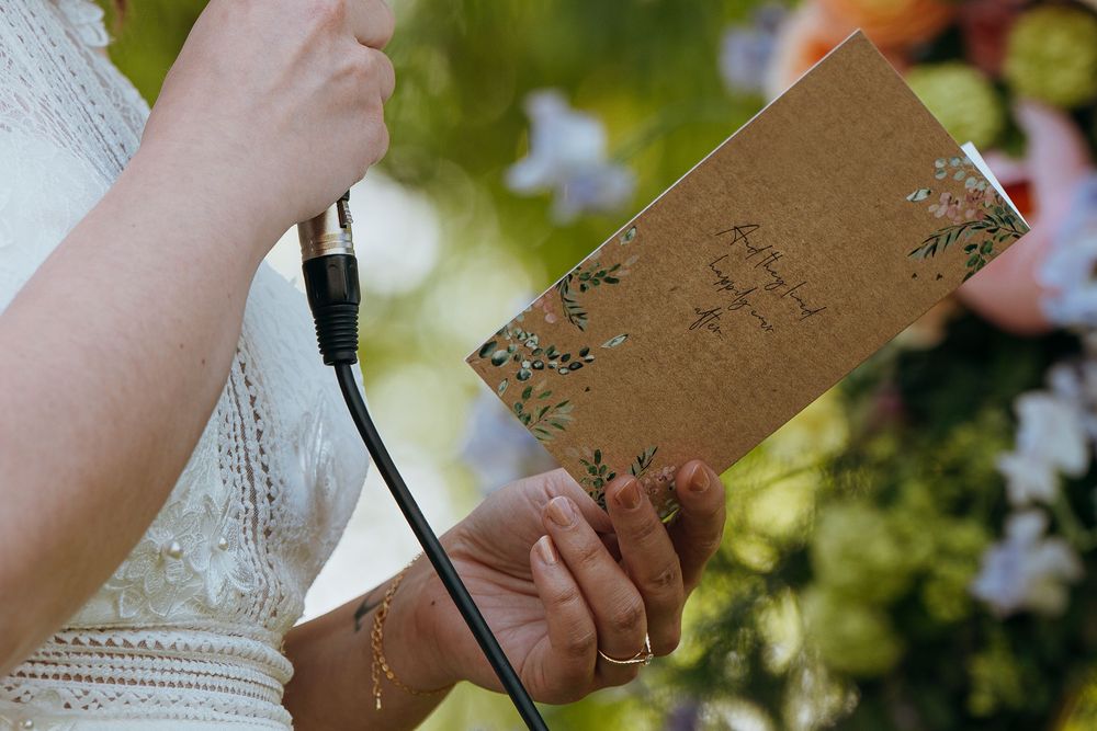 Hands holding a vintage-style brown journal or book with floral decorative details outdoors.