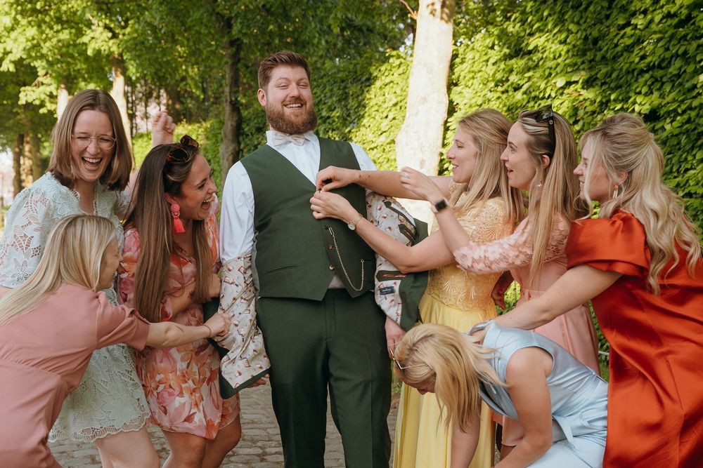 Wedding guests enjoying a lively outdoor celebration under trees with natural lighting.