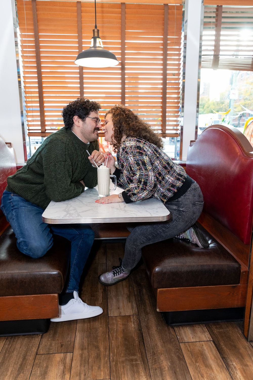 Engaged Couple kisses over a milkshake at Bel-Aire Diner in Astoria, Queens.