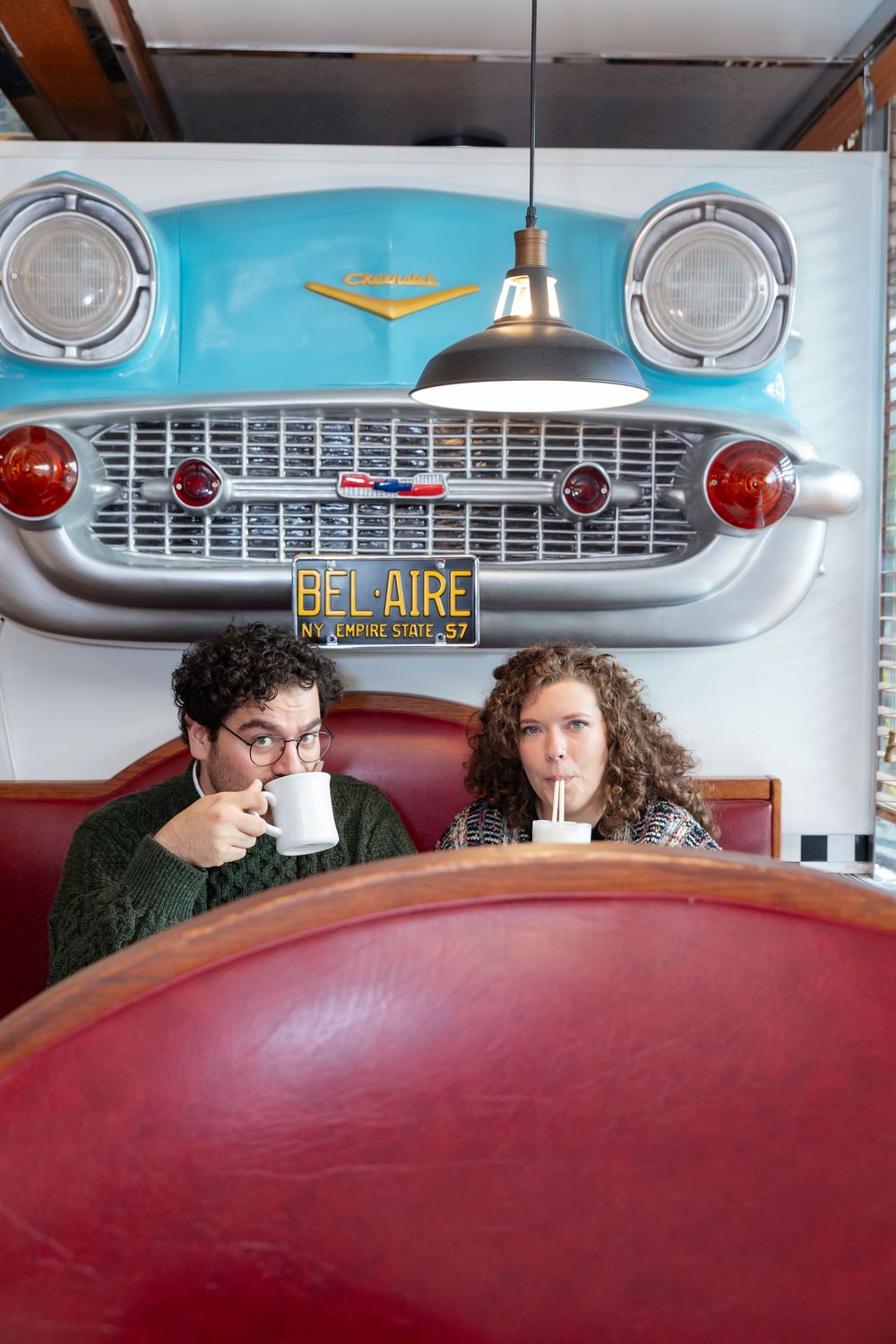 Engaged Couple sips coffee during photo session at Bel-Aire Diner in Astoria, Queens.