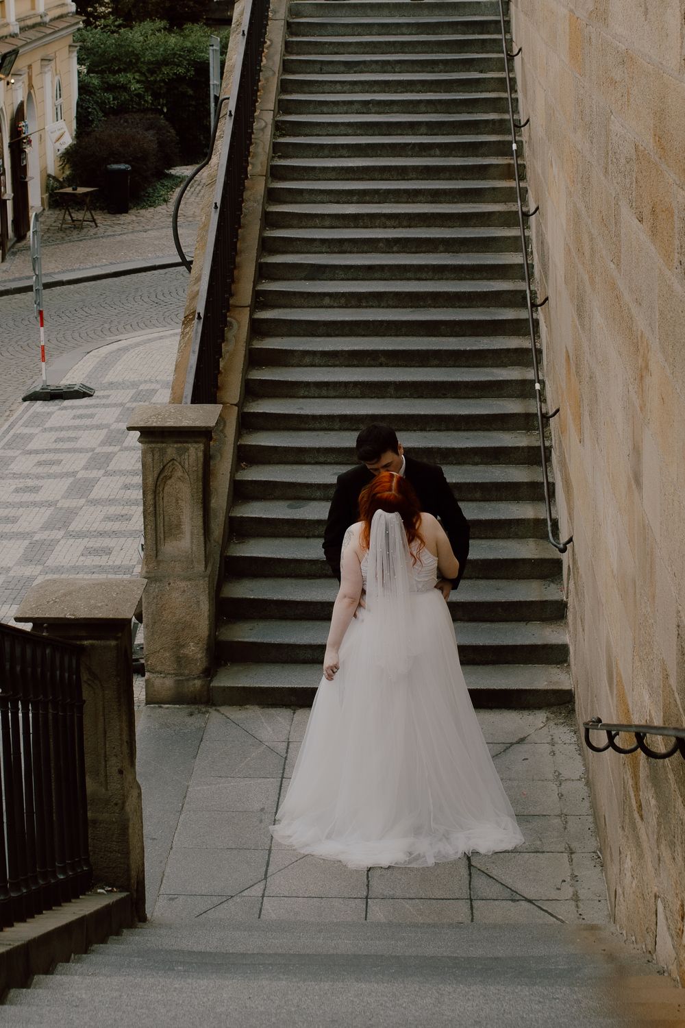 A bride in a white wedding dress descends a curved stone staircase in a sequence of four similar shots.