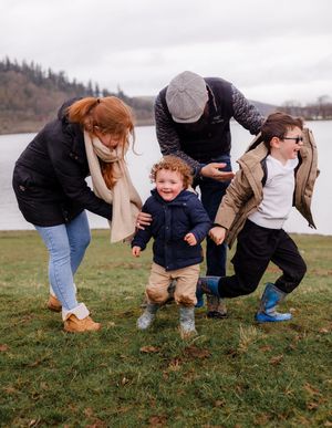 Family walking on grass with toddler in front fun family photoshoot